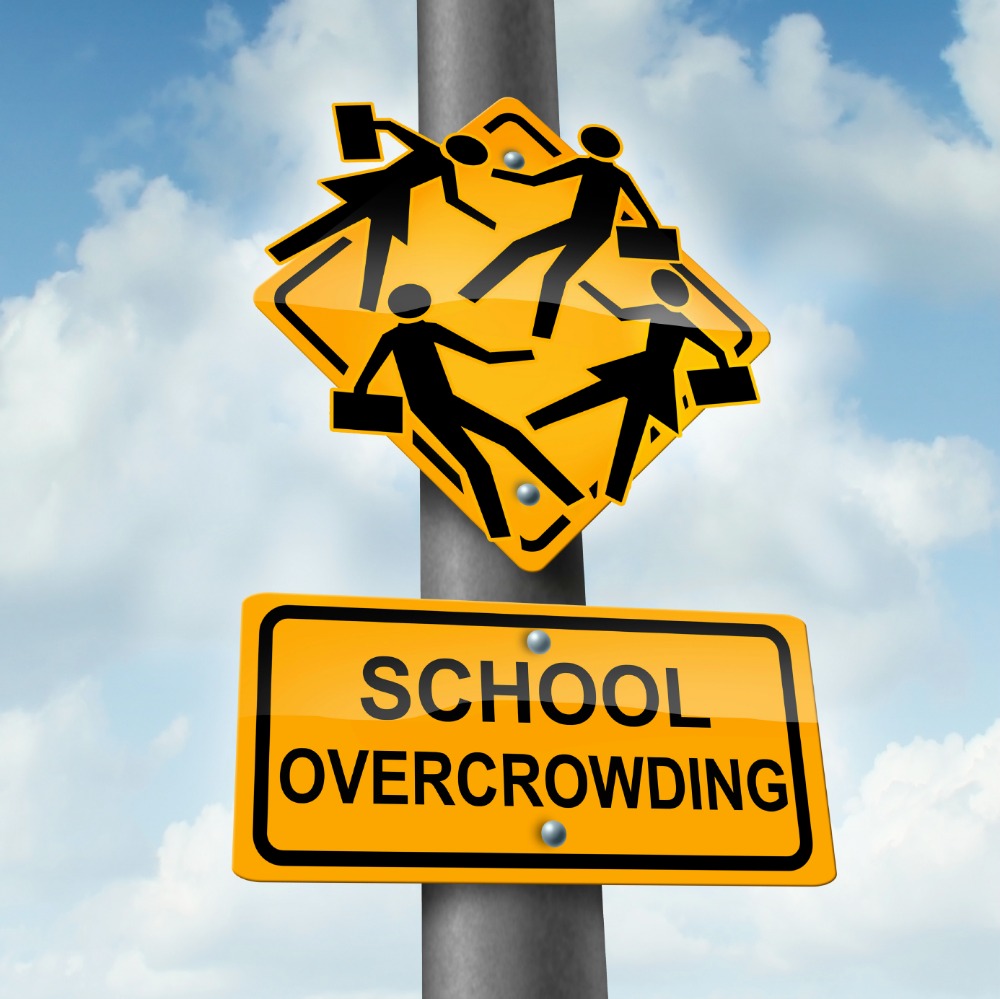 School overcrowding and classroom overcrowding concept as a crossing traffic sign with overcrowded students bursting out of the seams as a symbol of the problems of public education financing and lack of teachers.